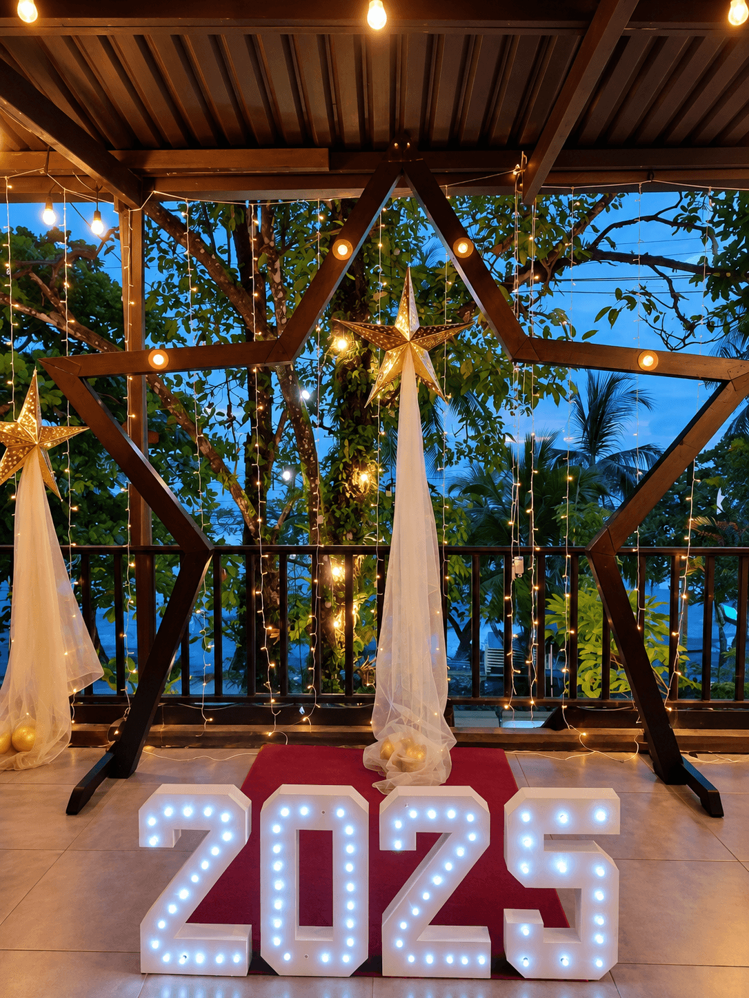 Letras luminosas de 2025 bajo un arco con flores y telas doradas