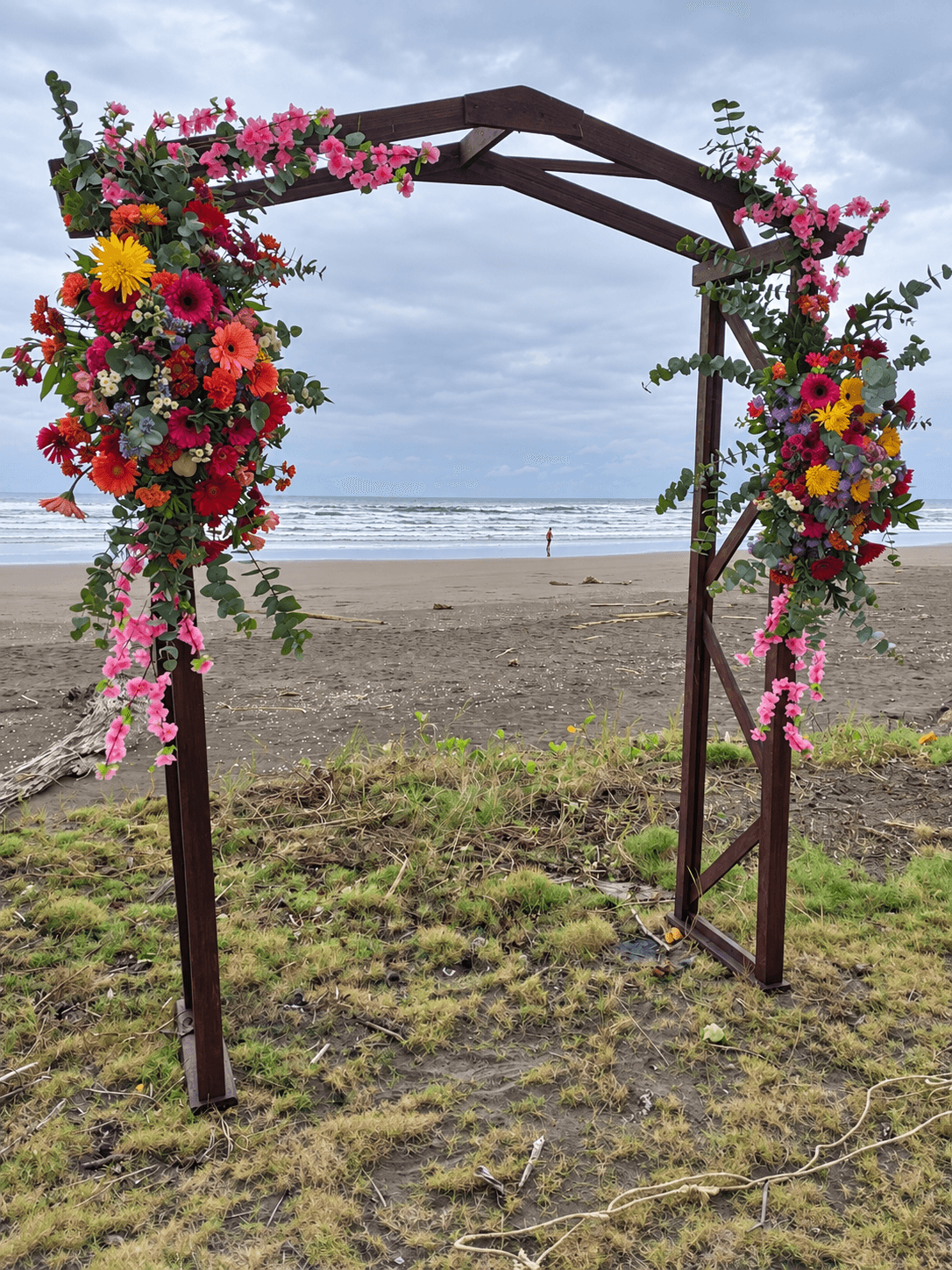 Arco de madera con flores de colores frente al océano