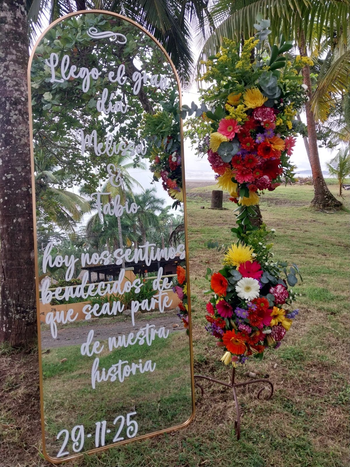 Espejo de bienvenida rodeado de flores de colores en una celebración al aire libre